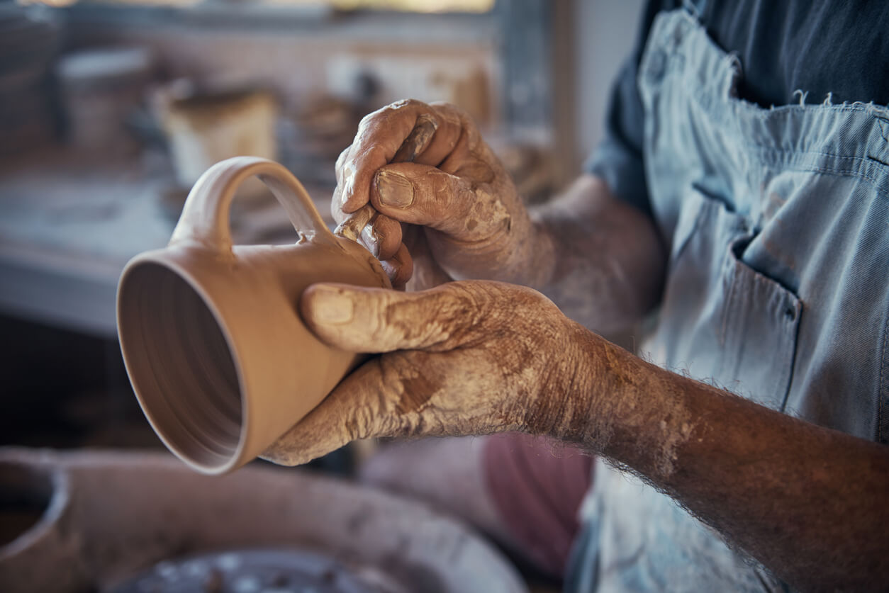 Person producing handmade pottery and mugs in a workshop.